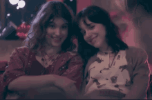 two women are sitting next to each other and smiling at the camera