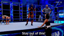 a woman is kneeling down in a wrestling ring while a referee watches .