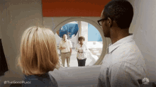a man and a woman are looking out of a window at a group of people .