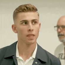 a young man wearing a white shirt and a black jacket has a badge on his jacket that says r.