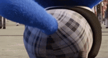 a close up of a blue stuffed animal 's butt in a plaid shirt and shorts .