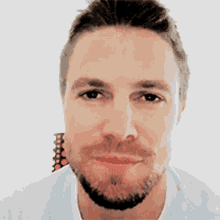a close up of a man 's face with a beard wearing a light blue shirt