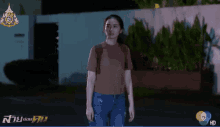 a woman in a brown shirt and blue jeans is standing in front of a sign that says 7 hd