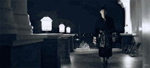 a man in a robe is walking down a balcony at night with the word poo visible in the corner