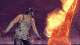 a man wearing a gas mask stands in front of a statue on fire