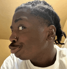 a man with dreadlocks and a nose ring makes a face