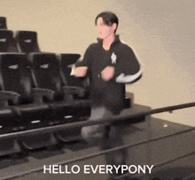 a man in a black jacket is dancing in front of a row of black chairs with the words hello everypony written on the bottom