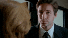a man in a suit and tie is looking at a woman in a white shirt