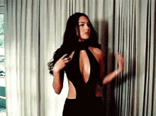 a woman in a black dress is standing in front of a window .