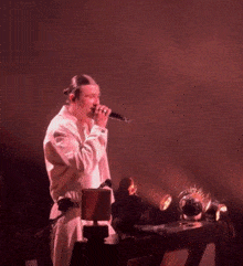 a man in a white jacket stands in front of a microphone