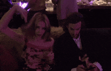 a woman in a floral dress is sitting next to a man in a suit and tie
