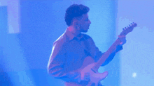 a man is playing an electric guitar in a blue room