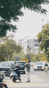 a man is standing on the side of a busy city street talking on a cell phone .
