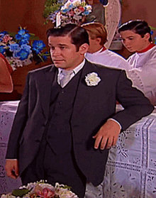 a man in a suit and tie leans on a table