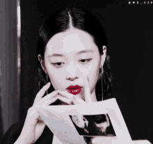 a woman with red lips is holding a piece of paper in her hand
