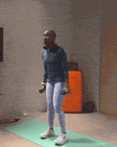 a man is standing on a yoga mat holding dumbbells