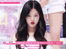 a girl with long black hair and red lips is standing in front of a sign that says b on it