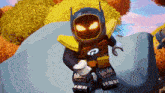 a lego robot with glowing eyes is sitting on a rock with trees in the background