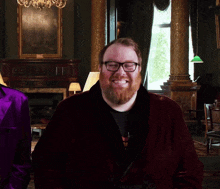 a man with glasses and a beard is smiling