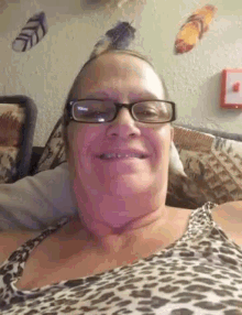an older woman wearing glasses and a leopard print shirt smiles