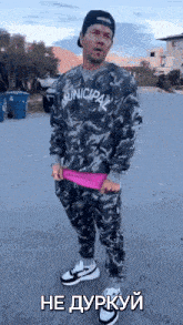 a man wearing a camouflage sweater and pants is standing on the side of the road .