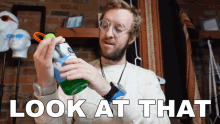 a man is holding a green bottle with the words look at that written on the bottom