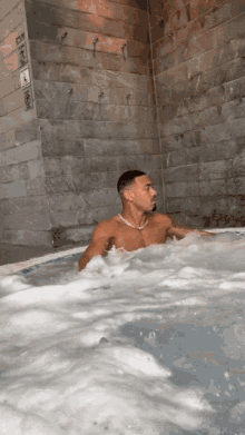 a shirtless man is sitting in a hot tub surrounded by water