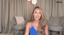 a woman in a blue dress is sitting in a living room holding her head .