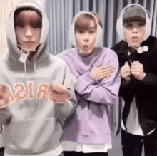 three young men are standing next to each other wearing headphones .
