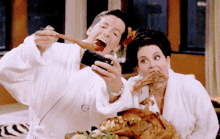 a man and a woman in bathrobes are eating turkey