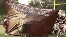 a football team carrying a banner that says ' eagle bridge high '