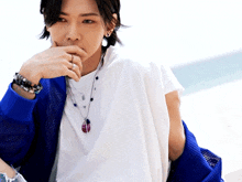 a woman wearing a white shirt and a blue jacket is covering her mouth with her hand