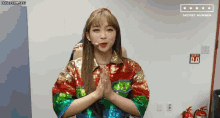a girl in a colorful sequined shirt is standing in front of a microphone .