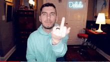 a man in a blue hoodie is giving the middle finger in front of a neon sign that says delulu