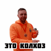 a man in an orange hoodie is holding a glass of wine and a medal around his neck