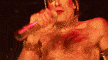 a shirtless man is singing into a microphone while wearing a choker .