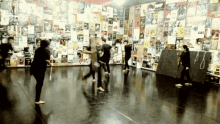 a group of people are dancing in front of a wall of posters