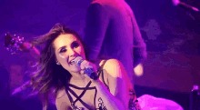a woman singing into a microphone while a man holds her arm