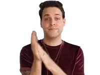 a man wearing a maroon t-shirt is clapping his hands in front of a white background