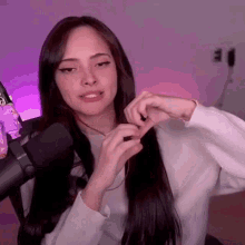 a woman is sitting in front of a microphone making a heart with her hands .