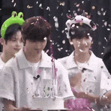 a group of people standing around a cake with confetti falling on them .