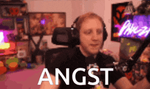 a man wearing headphones is sitting in front of a microphone with the word angst in front of him
