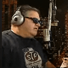 a man wearing headphones and sunglasses is talking into a microphone