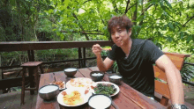 a man is sitting at a table with plates of food and bowls of liquid