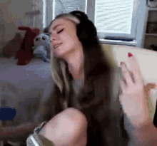 a woman is sitting on a couch wearing headphones and dancing .