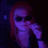 a woman with red hair wearing sunglasses and ear buds