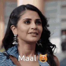 a woman wearing earrings and a nose ring has the word maal written on her face