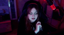 a woman wearing headphones is giving the middle finger while sitting in a chair in front of a microphone .