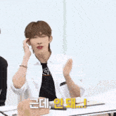 a man in a white shirt is sitting at a table with his hands on his ears and the words ohli ? written in korean