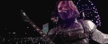 a man is playing a guitar in front of a crowd at a concert .